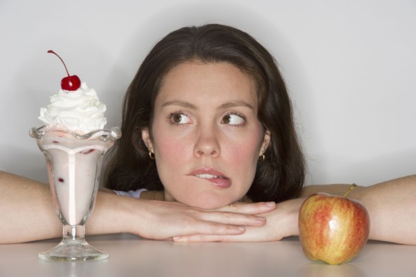 Woman choosing between ice cream and apple.
