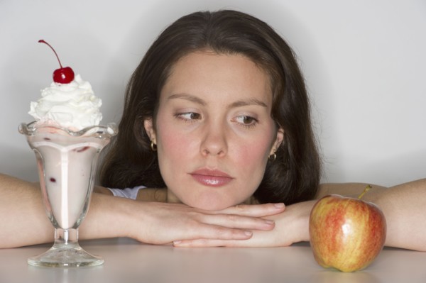 Woman choosing between ice cream and apple.