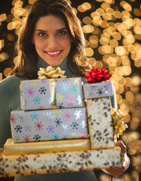 Portrait of young woman carrying Christmas presents. Photo : Daniel Grill