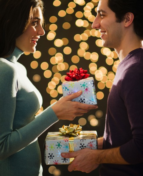 Young couple giving Christmas presents each other. Photo : Daniel Grill