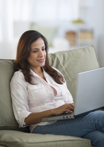 Woman sitting on sofa and using laptop.