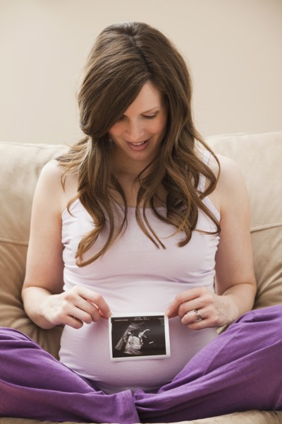 Young pregnant woman looking at CT image of unborn baby. Photo : Mike Kemp