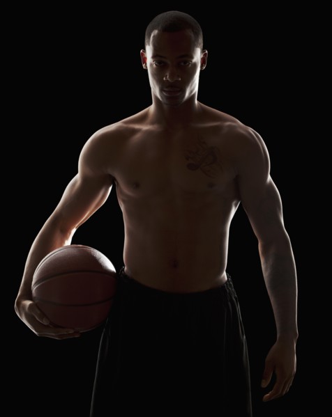 Studio portrait of shirtless man holding basketball. Photo : Mike Kemp