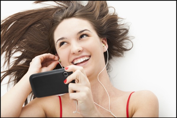 Young woman listening to mp3 player. Photo : Mike Kemp