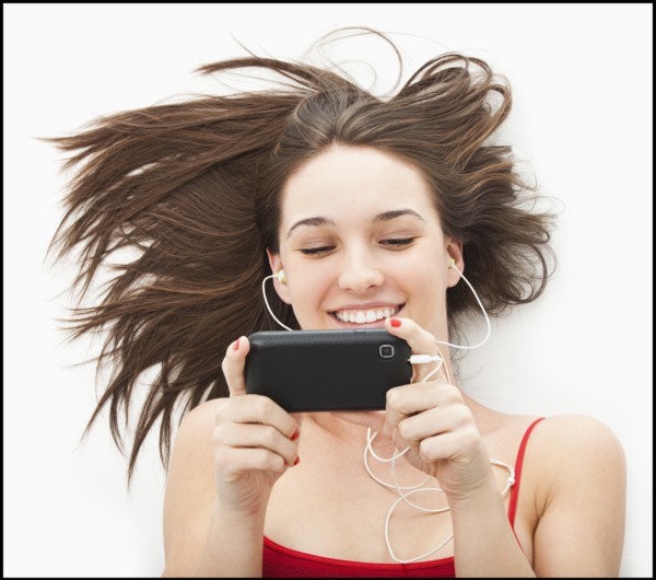 Young woman listening to mp3 player. Photo : Mike Kemp