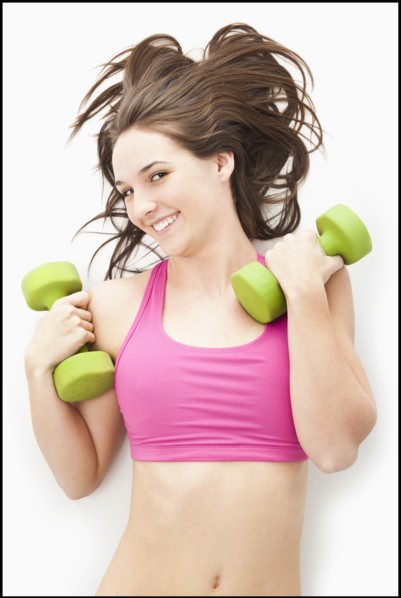 Studio portrait of young woman holding hand weights. Photo : Mike Kemp