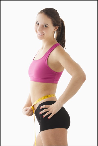Studio portrait of young woman measuring waist. Photo : Mike Kemp