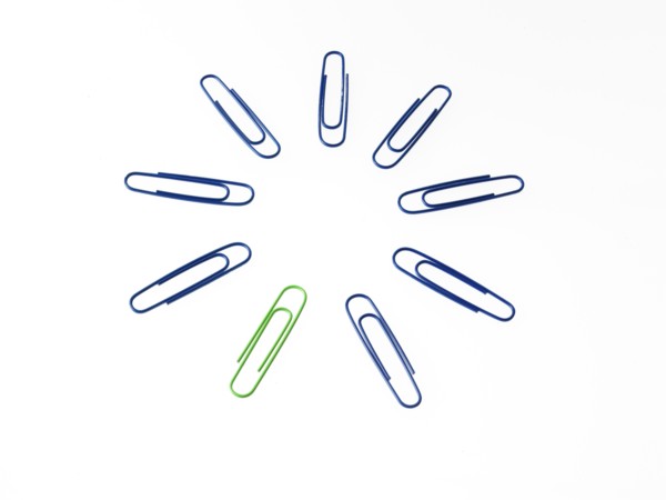 Blue and green paper clips on white background. Photo : David Arky