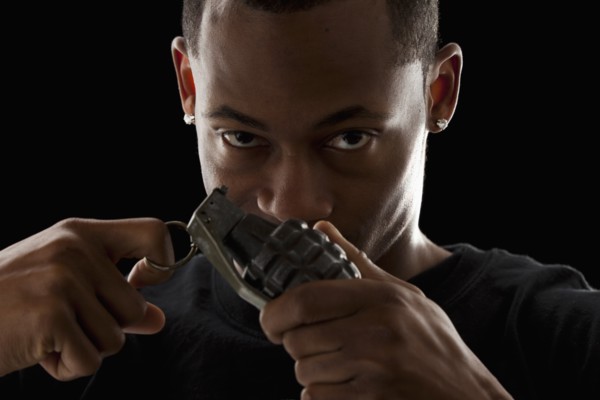 Studio portrait of young man holding grenade. Photo : Mike Kemp