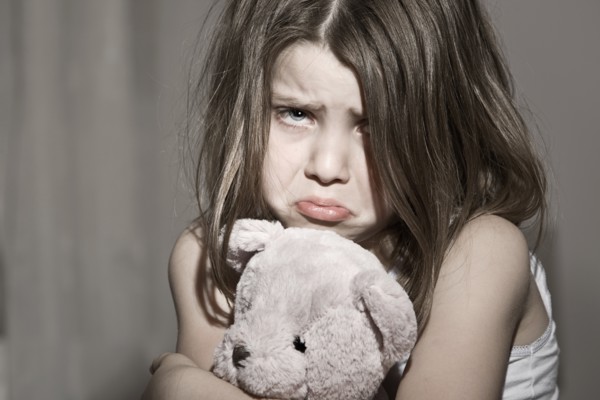 Studio portrait of sad girl (6-7) with pink teddy bear. Photo : Justin Paget