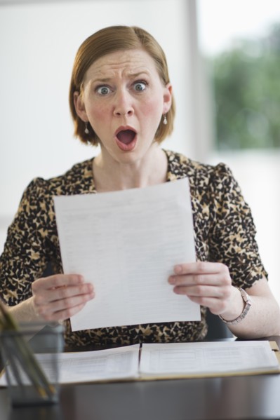 Woman reading document looking surprised.