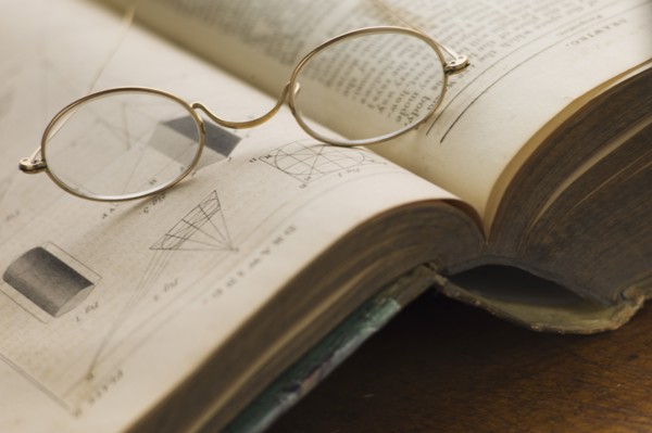 Close up of antique glasses lying on open book.