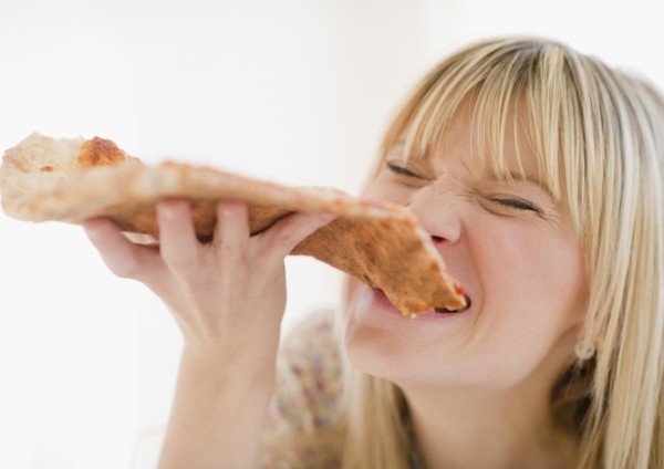 Young woman eating pizza. Photo : Jamie Grill Photography