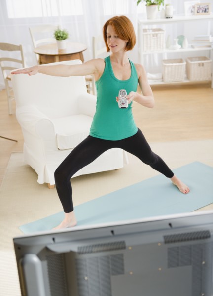 Woman watching tv and exercising. Photo : Jamie Grill Photography
