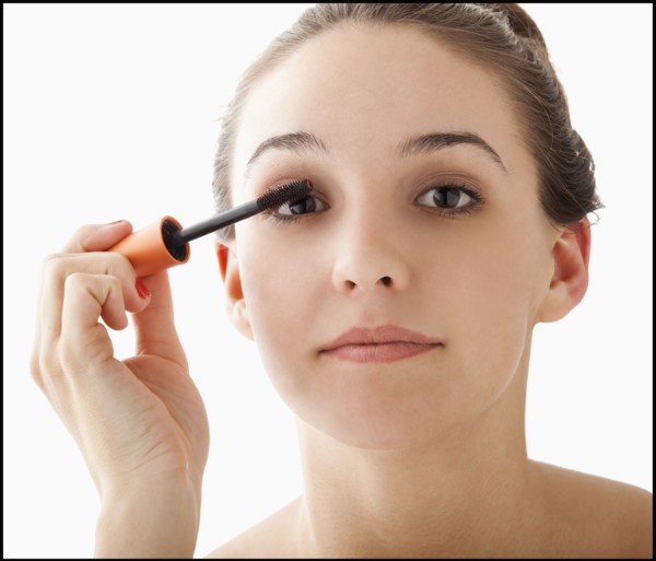 Studio portrait of young woman applying mascara. Photo : Mike Kemp