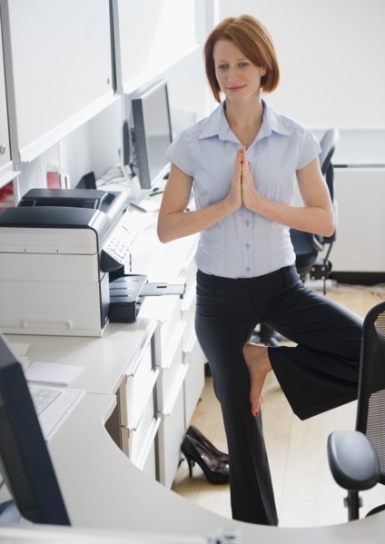 Businesswoman doing yoga position in office. Photo: Jamie Grill Photography