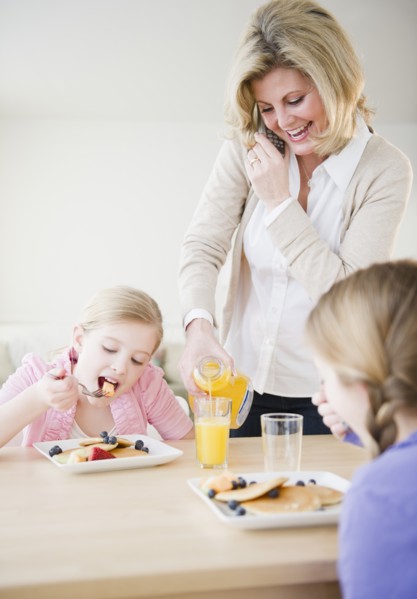 Mother and daughters (8-11) eating breakfast. Photo : Jamie Grill Photography