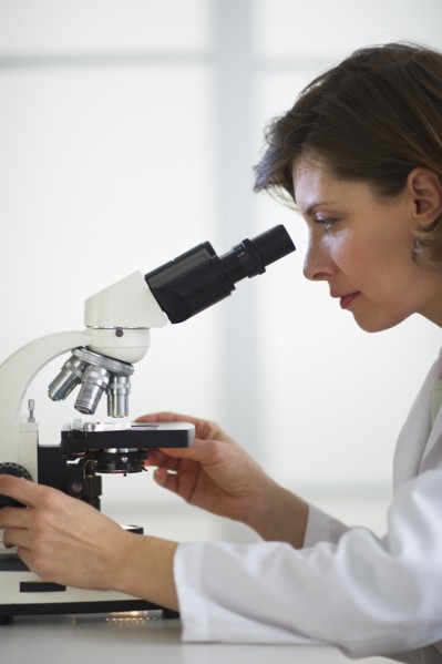 Woman in laboratory looking through microscope.