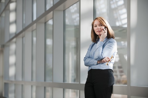 Businesswoman talking on phone in corridor. Photo: Mark Edward Atkinson