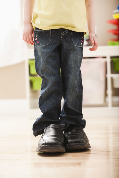 Girl (2-3) standing in dad's shoes, low section. Photo: Mike Kemp