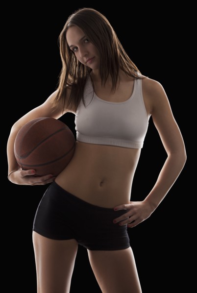 Studio portrait of young woman holding basketball. Photo : Mike Kemp