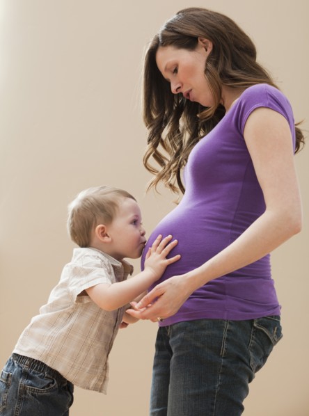 Portrait of boy (2-3) kissing pregnant mother's belly. Photo : Mike Kemp