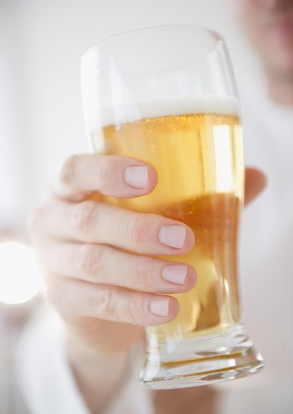 Hand holding glass of beer. Photo : Jamie Grill Photography