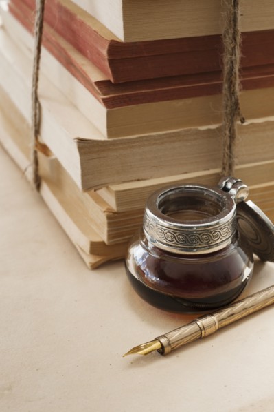 Close up antique ink well, pen and books.