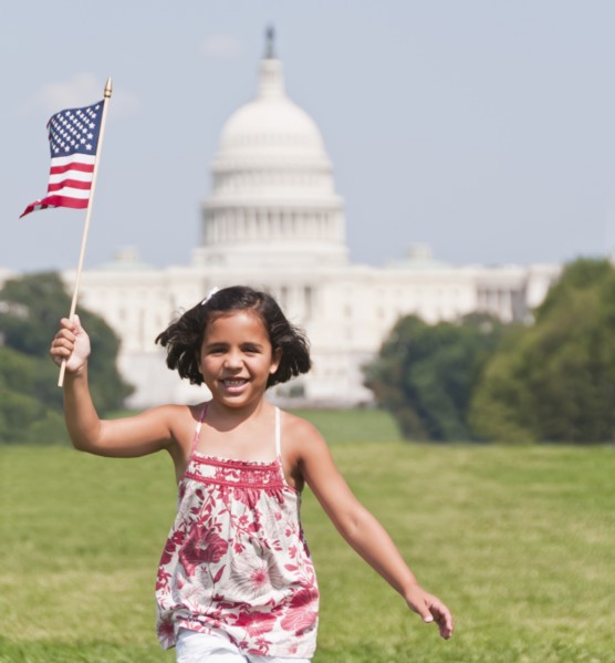 USA, Washington DC, girl (10-11) with US flag running in front of Capitol Building. Photo : Chris