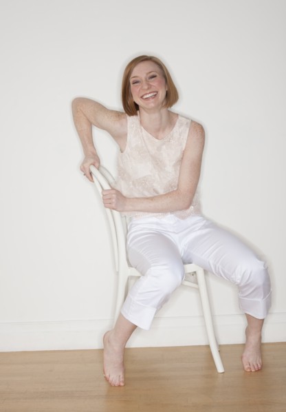 Studio shot of woman sitting on chair and smiling.