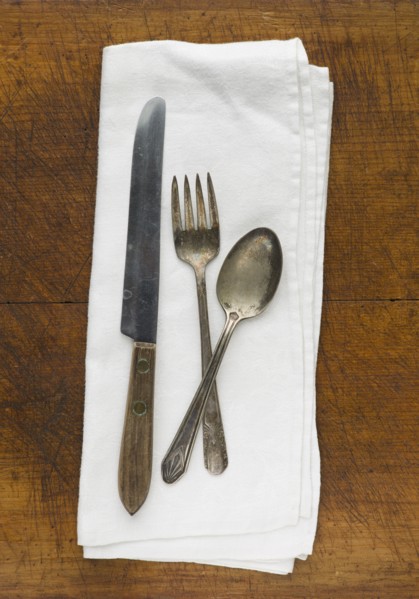 Close up of silver forks, knife and spoon on napkin.