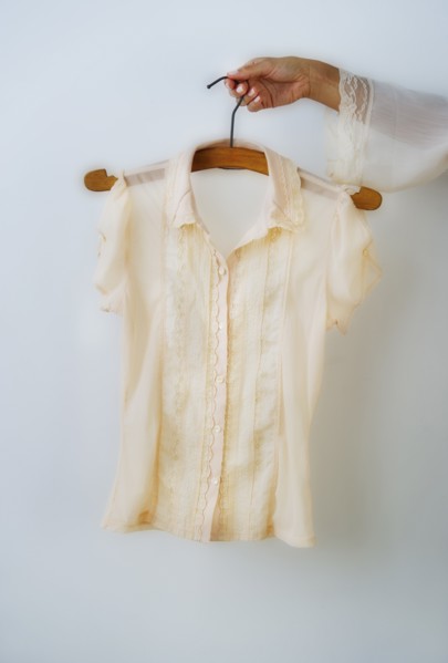 Woman's hand holding coathanger with blouse.