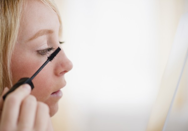 Young woman applying mascara. Photo : Jamie Grill Photography