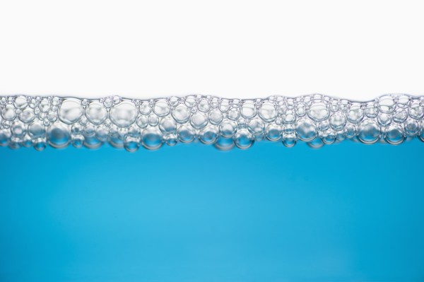 Close up of soap bubbles on water surface.