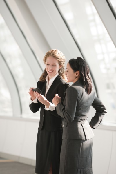 Businesswomen looking at cell phone. Photo : Mark Edward Atkinson