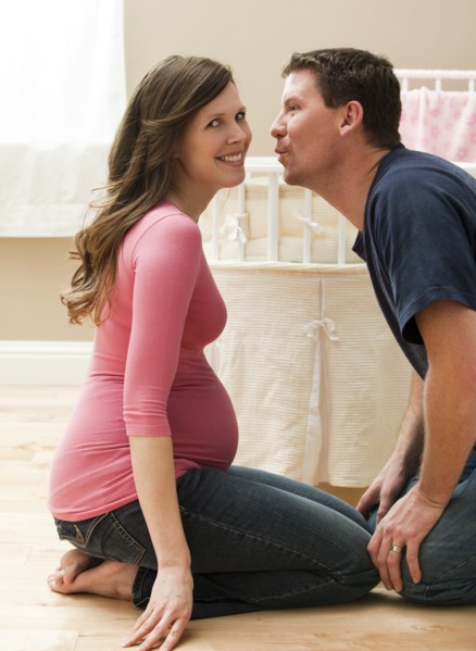 Young pregnant woman about to be kissed by mid adult man. Photo : Mike Kemp