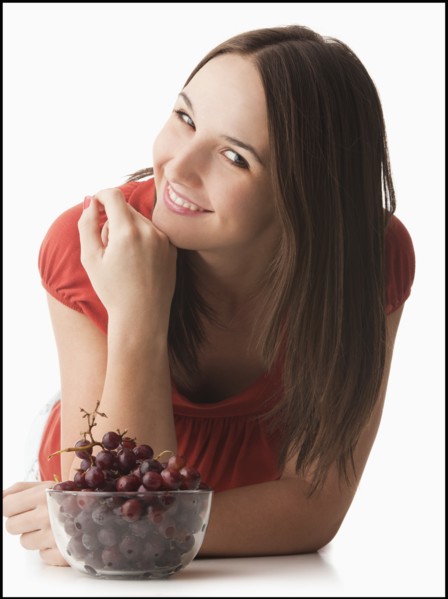 Studio portrait of young woman with grapes. Photo : Mike Kemp
