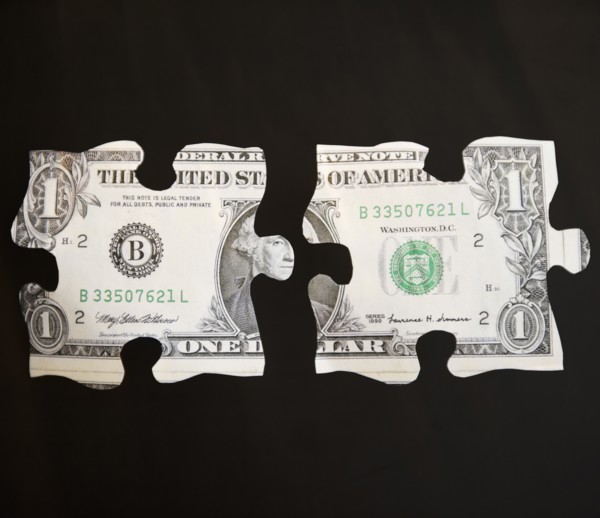 Studio shot of jigsaw pieces depicting one dollar bill. Photo : Jamie Grill Photography