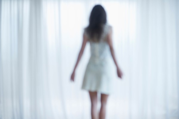 Young woman standing and looking through window.