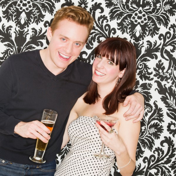 Studio portrait of young couple holding drinks. Photo : Daniel Grill