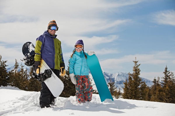 USA, Colorado, Telluride, Father and daughter (10-11) posing with snowboards in winter scenery.