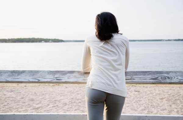 USA, New York State, Long Island, woman leaning against rail fence and looking at lake. Photo :