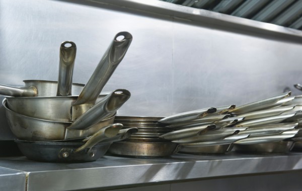 Close up frying pans on shelf in commercial kitchen.