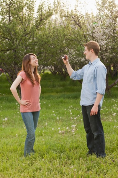 USA, Utah, Provo, Young man photographing young woman in orchard. Photo : Mike Kemp