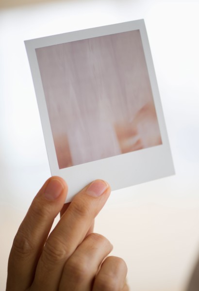 Studio shot of man's hand holding Polaroid photograph.