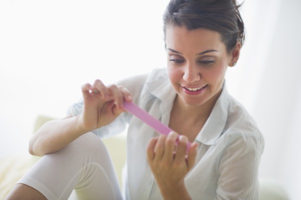 Attractive young woman filing nails.