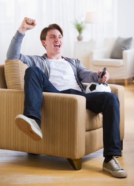 Man sitting in chair and watching TV soccer game. Photo : Daniel Grill