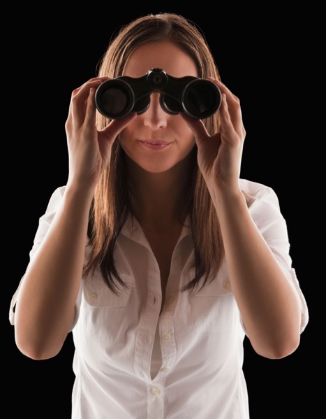 Young attractive businesswoman looking through binoculars. Photo : Mike Kemp
