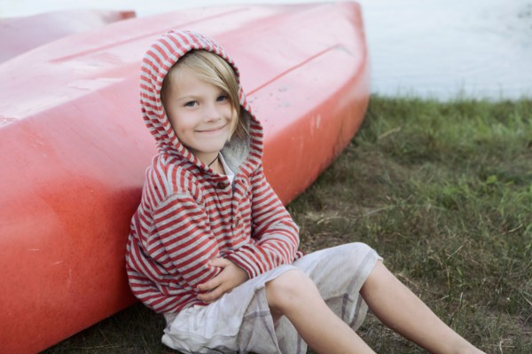 Portrait of boy (4-5) sitting by canoe. Photo : King Lawrence
