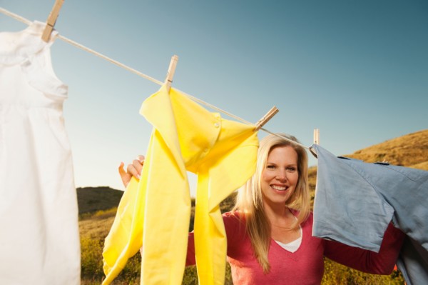 Woman hanging laundry on clothesline .